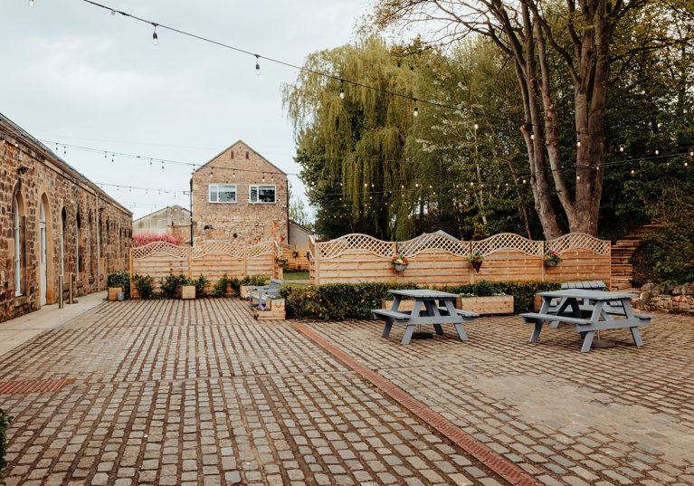 Courtyard area of The Venue, Eskmills, decorated with picnic tables and hanging baskets